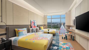 A hotel room with two beds, a TV, a desk, and a view of the city.