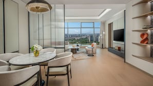 A modern living room with a dining area, large windows with a city view, a flat-screen TV, and a minimalist design. - Crowne Plaza Guangzhou Window Of Canton by IHG (Guangzhou)