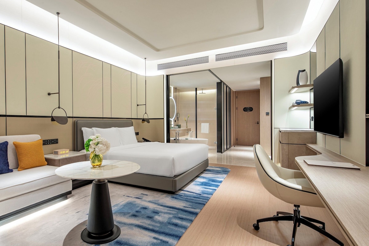 Een moderne hotelkamer met een bed, bank, bureau en een televisie.