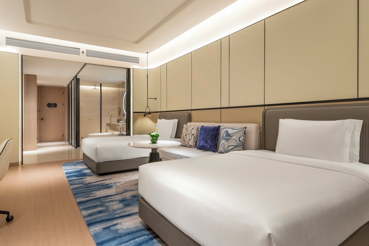Een hotelkamer met een groot bed, een bureau, een stoel, een televisie en een badkamer met douche en toilet.