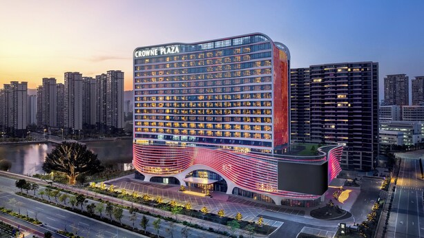 Un hotel moderno con fachada curva, varios pisos y un área de entrada destacada.