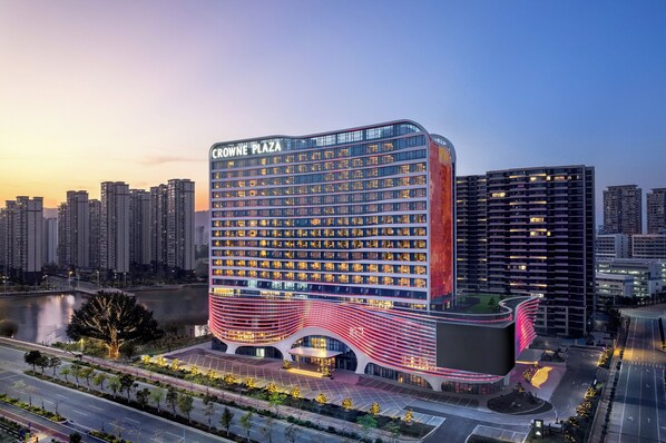Un hotel moderno con fachada curva, varios pisos y un área de entrada destacada.