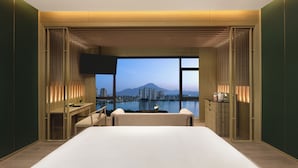 Habitación de hotel moderna con una cama grande, un escritorio y vistas a la ciudad y a las montañas.