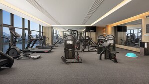 Un gimnasio moderno con máquinas de cardio, pesas y un espejo grande.