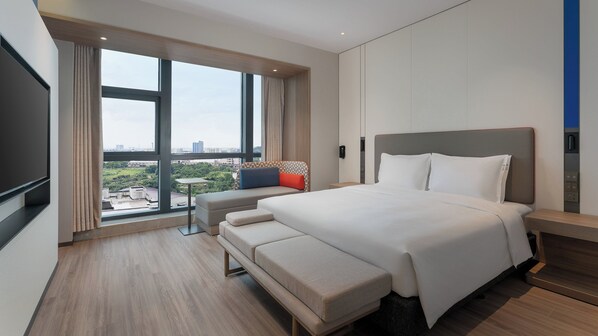 A modern hotel room with a large bed, a bench, a small table, and a TV. - Holiday Inn Express Foshan Sanshui by IHG (Foshan)
