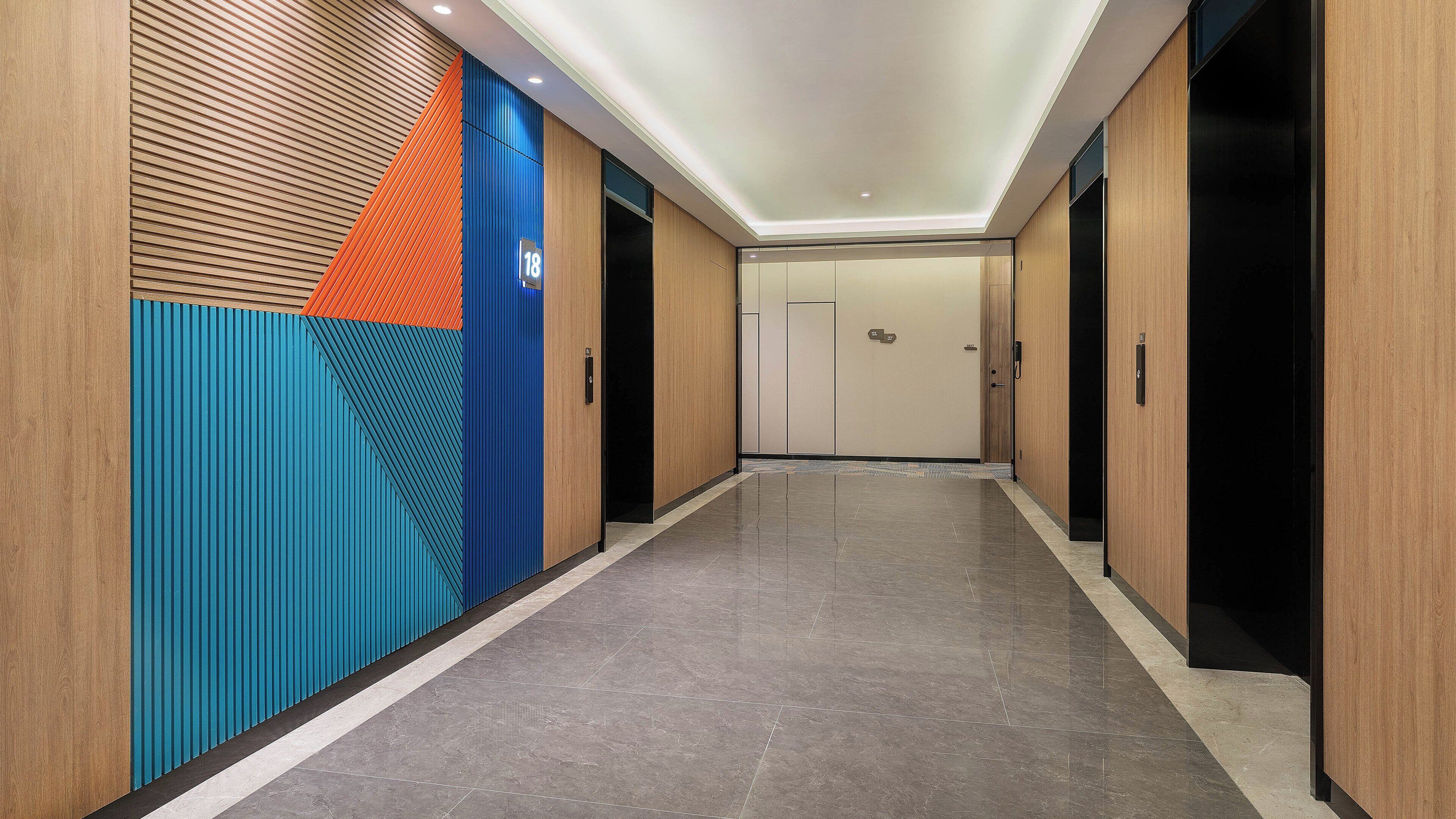 A hallway with a modern design, featuring a combination of wooden paneling and colorful geometric patterns on the walls.