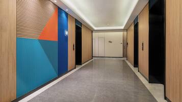A hallway with a modern design, featuring a combination of wooden paneling and colorful geometric patterns on the walls.