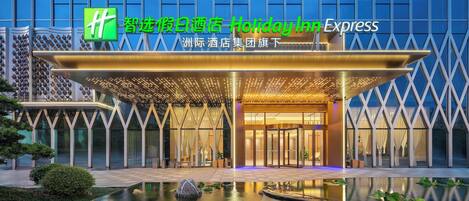 A hotel entrance with a modern design, a water feature in front, and illuminated signage.