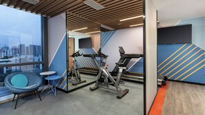 A modern gym with exercise equipment, a seating area, and a city view through large windows. - Holiday Inn Express Foshan Sanshui by IHG (Foshan)