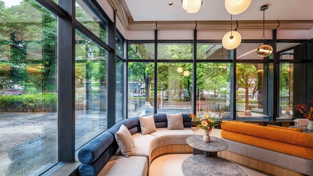 Un intérieur moderne avec de grandes fenêtres, un espace salon aux lignes courbes et une table ronde.