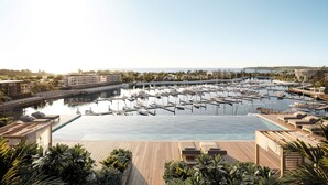 A marina with multiple boats docked, a large swimming pool, and lounge areas with sunbeds. - Crowne Plaza Shell Cove Marina by IHG (Shell Cove)