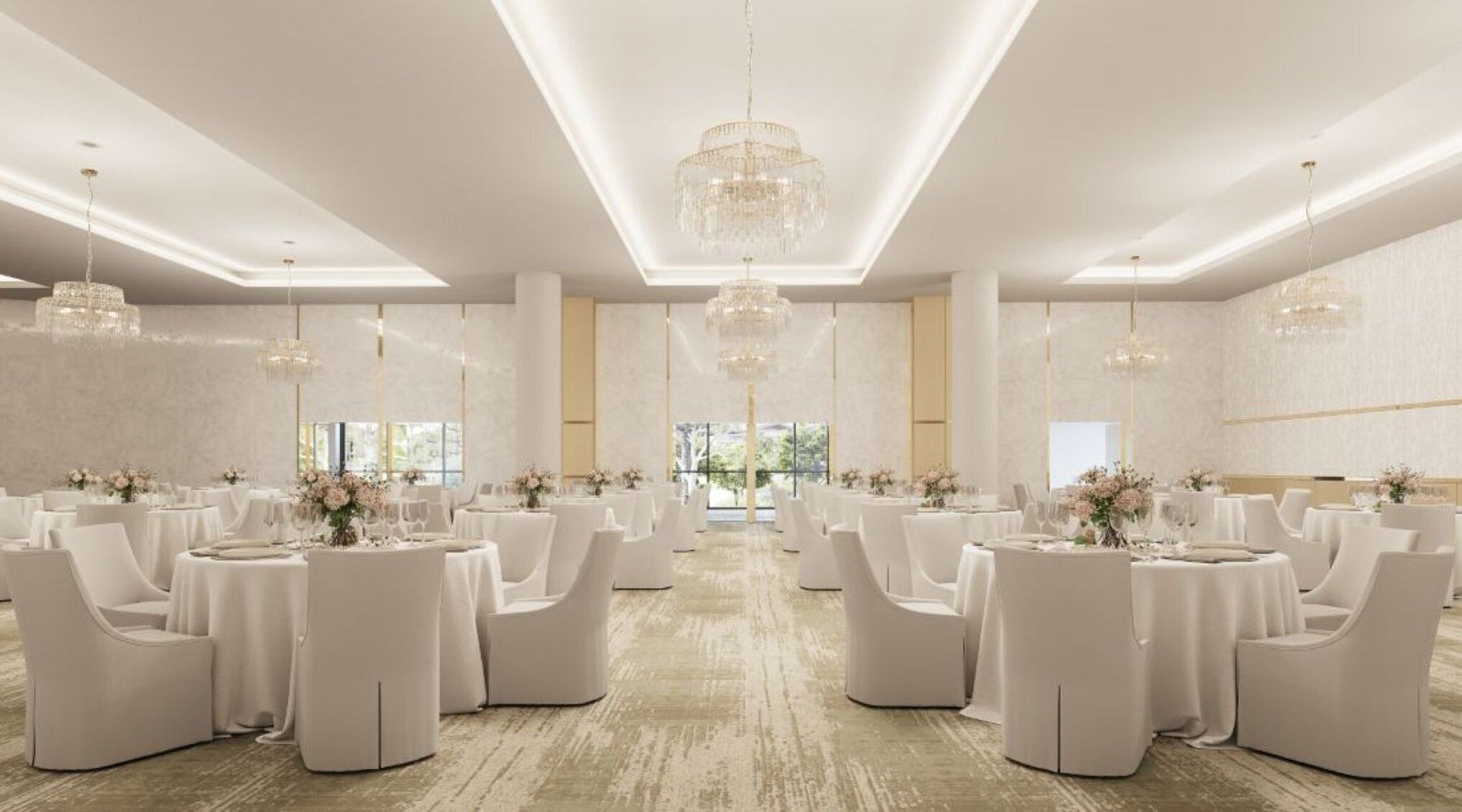 A spacious banquet hall with round tables and white chairs, large chandeliers, and a view of greenery outside.