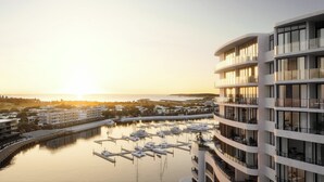 A modern hotel with multiple balconies overlooking a marina with boats. - Crowne Plaza Shell Cove Marina by IHG (Shell Cove)