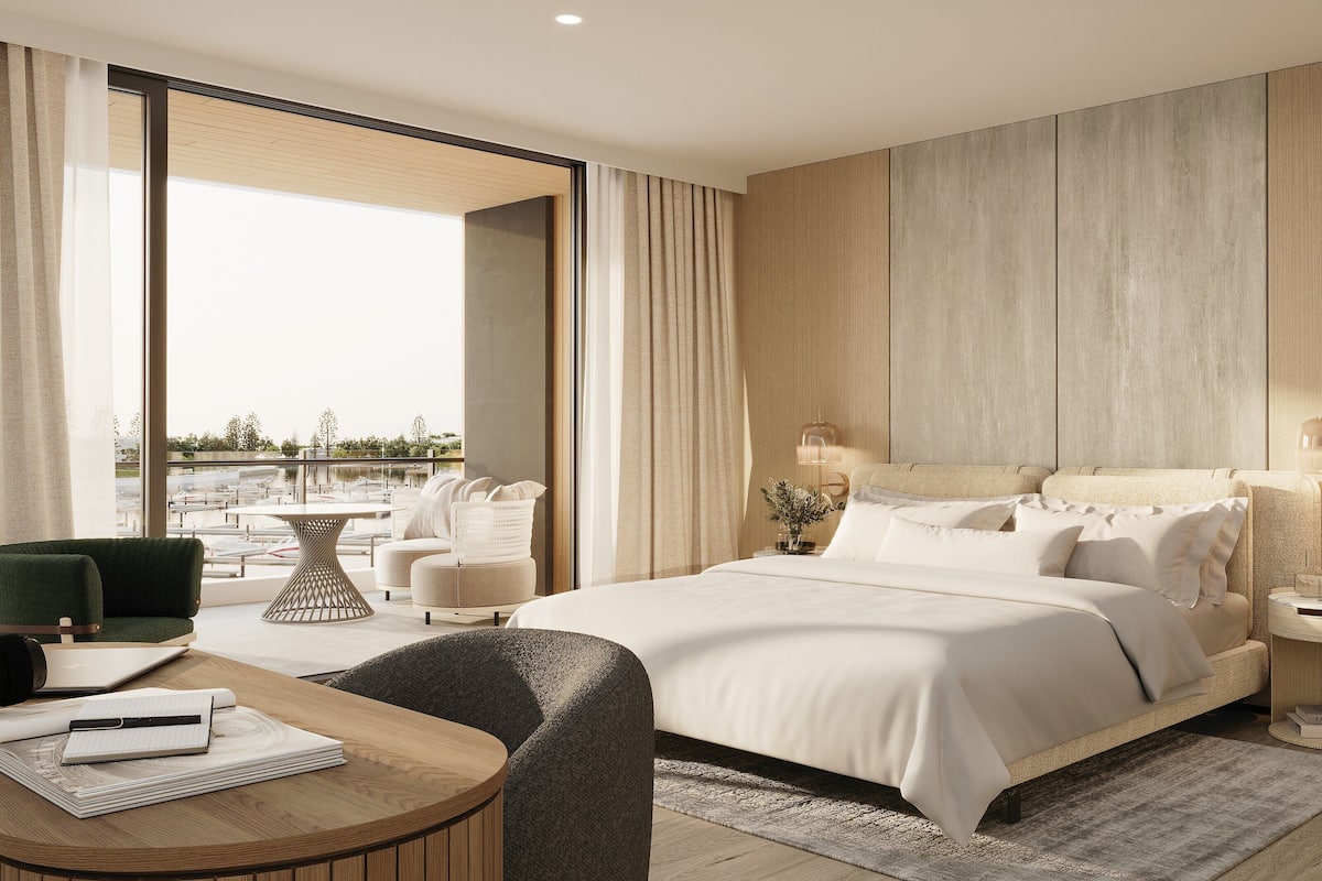 Une chambre d’hôtel moderne dotée d’un grand lit, d’un coin salon avec une table et offrant une vue sur l’extérieur.