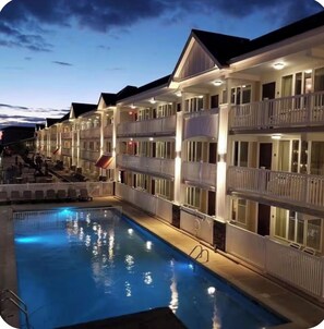 A hotel with a swimming pool, multiple balconies, and a well-lit exterior. - Avalon Beach Condo (Avalon)