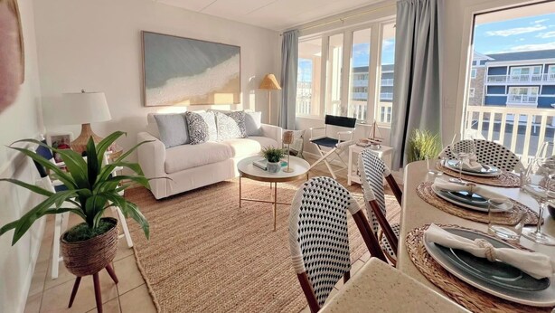A well-lit living room with a sofa, coffee table, and dining area set up for a meal. - Avalon Beach Condo (Avalon)