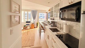 A modern kitchen with white cabinetry, a black stove top, and a view to the outside. - Avalon Beach Condo (Avalon)