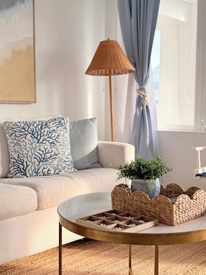 A living room with a sofa, a coffee table, a lamp, and a potted plant.