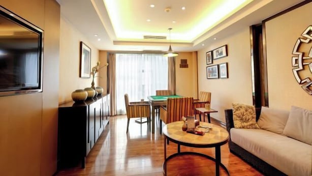 Une chambre d’hôtel moderne avec un plancher en bois, un canapé, une table basse ronde, une table à manger avec des chaises et une table de billard.