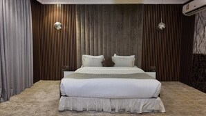 A modern bedroom with a large bed, wooden panel walls, and a marble accent wall. - Elaf Dammam Serviced Apartment (Dammam)