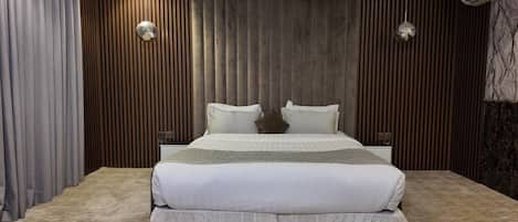A modern bedroom with a large bed, wooden panel walls, and a marble accent wall.