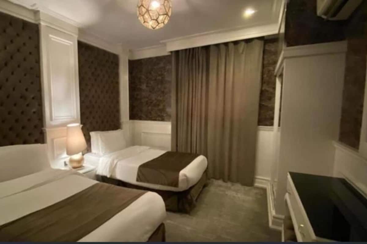 A hotel room with two beds, a desk, and a television.