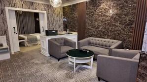 A modern room with a bed, two armchairs, a small table, and a desk with a computer. - Elaf Dammam Serviced Apartment (Dammam)