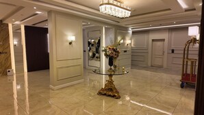 A luxurious lobby with a marble floor, a glass-top table with a floral centerpiece, and a chandelier. - Elaf Dammam Serviced Apartment (Dammam)