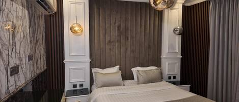 Ein Schlafzimmer mit einem großen Bett, Holzvertäfelung an den Wänden, einem Marmorboden und einer Chandelüster.