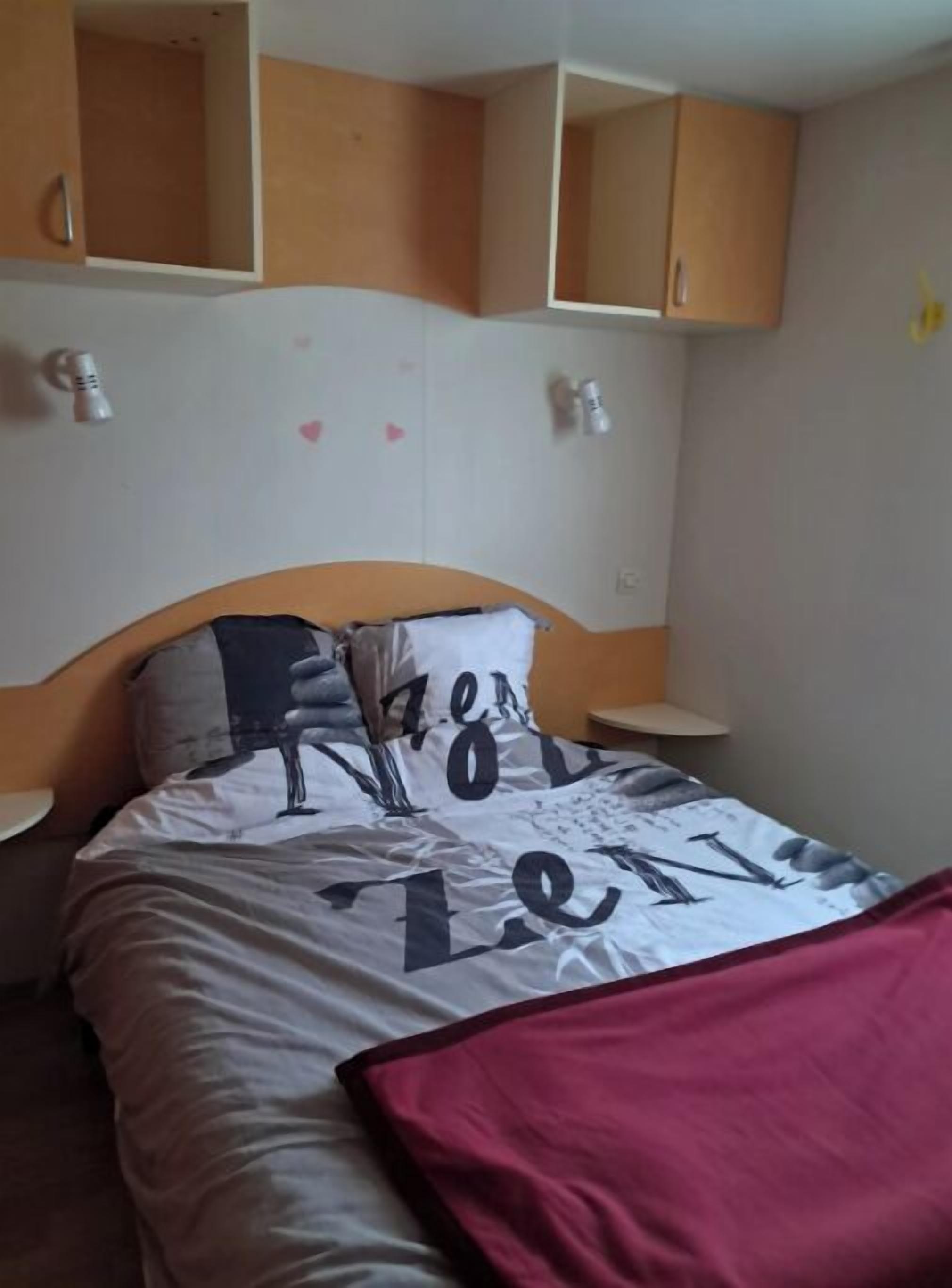 A bedroom with a bed, wooden cabinets, and a nightstand.