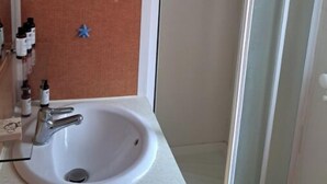 A bathroom with a white sink, a mirror, and a shower area. - Mobile home in the heart of nature (Minzac)