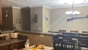 A kitchen with a wooden table, a toaster, and a chandelier.