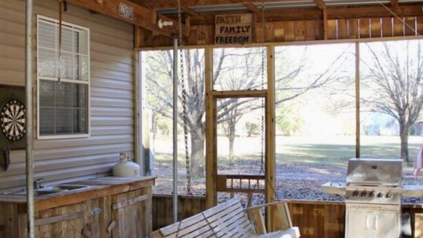 A rustic cabin with a wooden bench, a gas stove, and a dartboard.