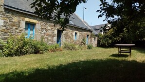 A stone building with blue windows and a grassy yard. - Traditional farmhouse with large garden. Porsliogan beach 500m away on foot. (Le Conquet)