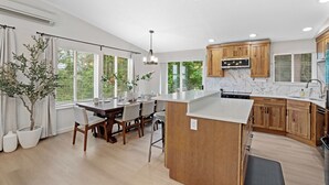 Una cocina moderna con armarios de madera, encimera de mármol y un comedor con mesa y sillas.