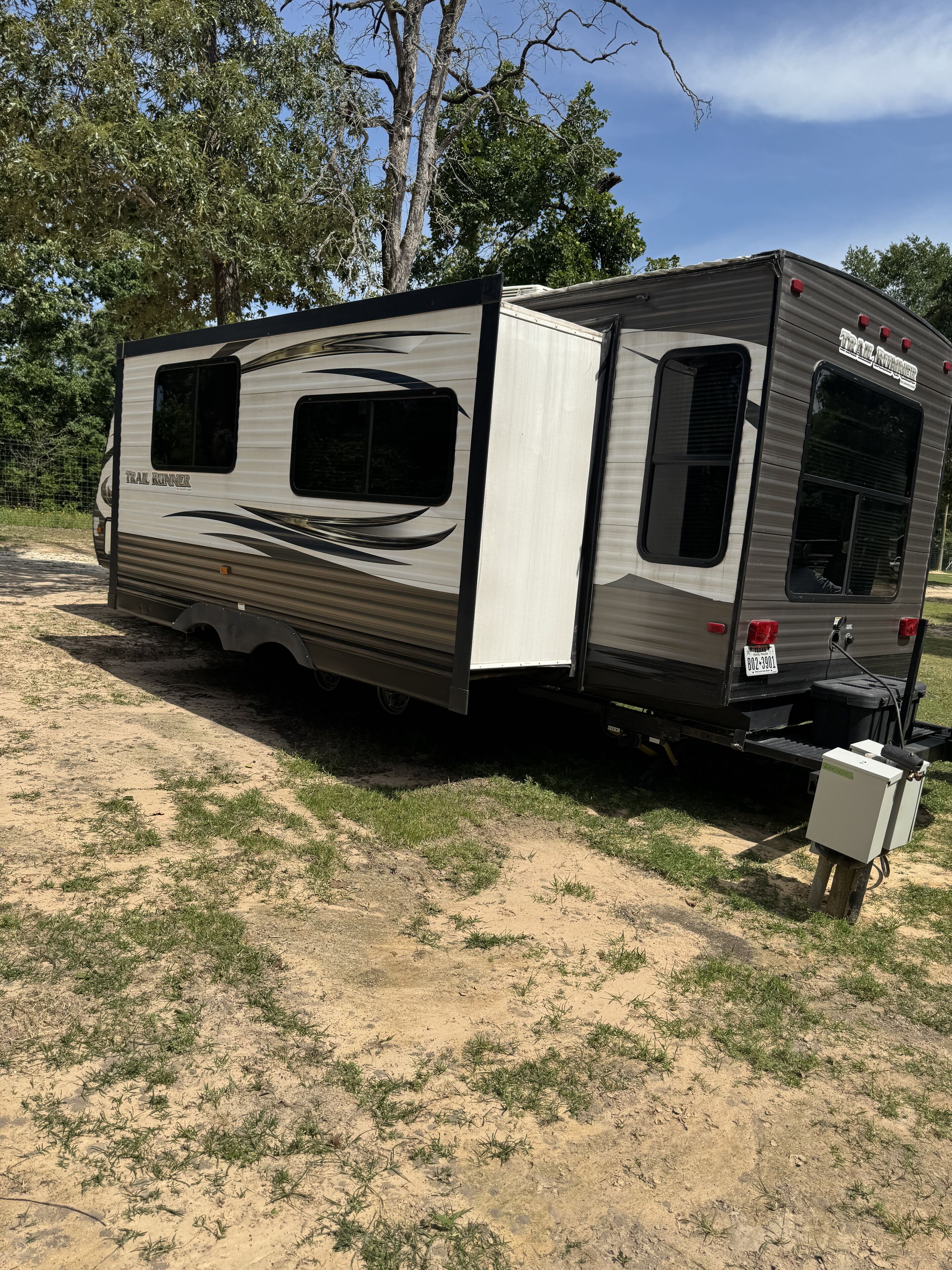 Een caravan met een schuifdeur, een klein raam en een kentekenplaat.