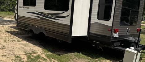 Een caravan met een schuifdeur, een klein raam en een kentekenplaat.