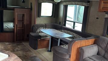 Interior compacto de una caravana con comedor, asientos y cocina americana.