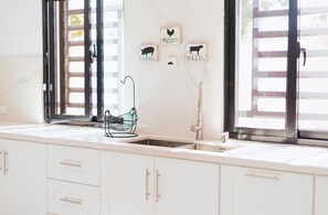 Enjoy cooking in this well-equipped kitchen with a stainless steel sink, black faucet, and ample natural light.