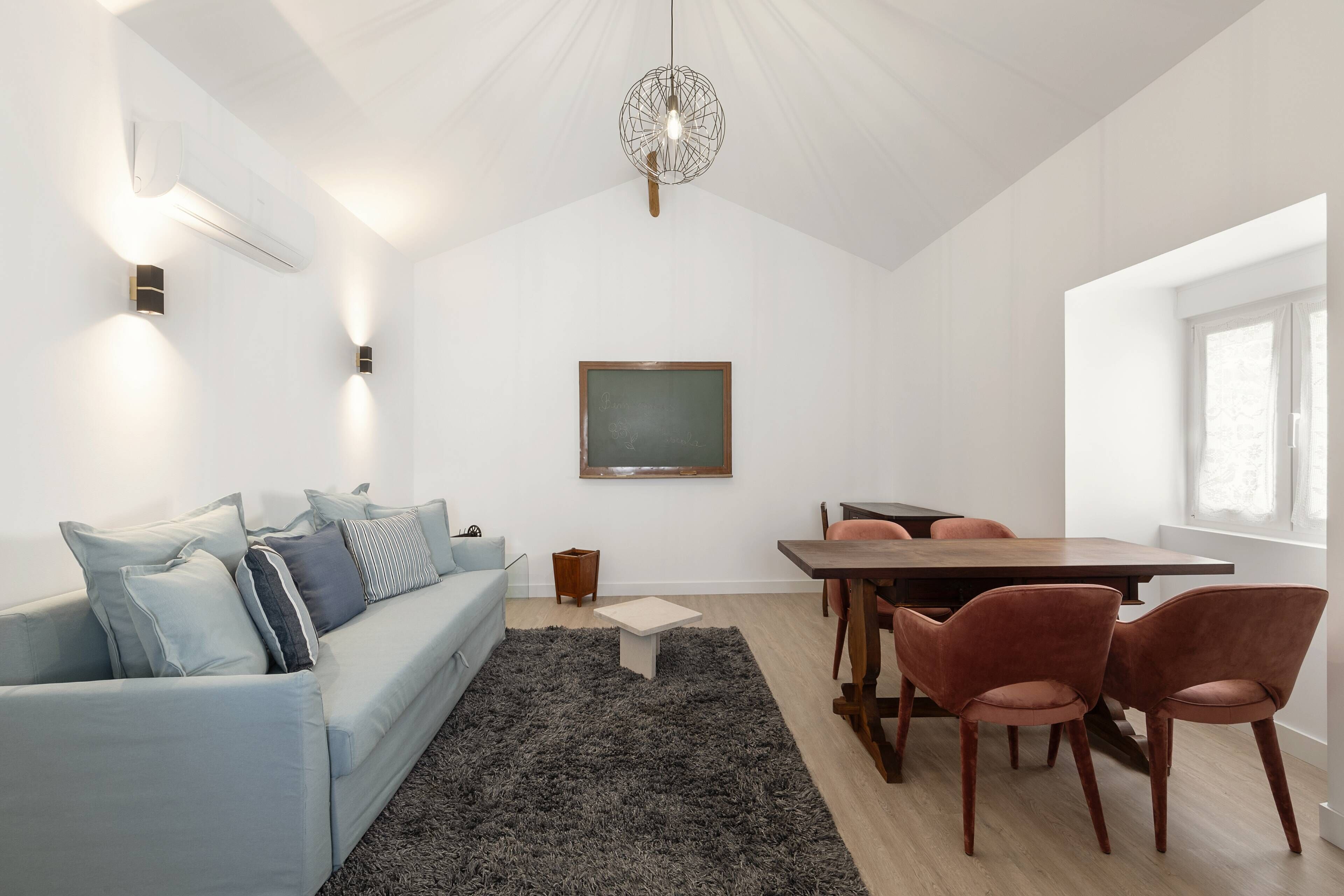 A modern living room with a sofa, coffee table, and dining table with chairs.