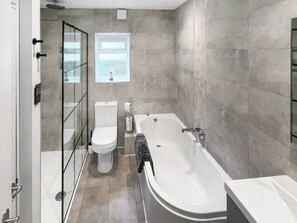 Ein modernes Badezimmer mit Duschkabine aus Glas, Toilette, Badewanne und einem Fenster für Tageslicht.