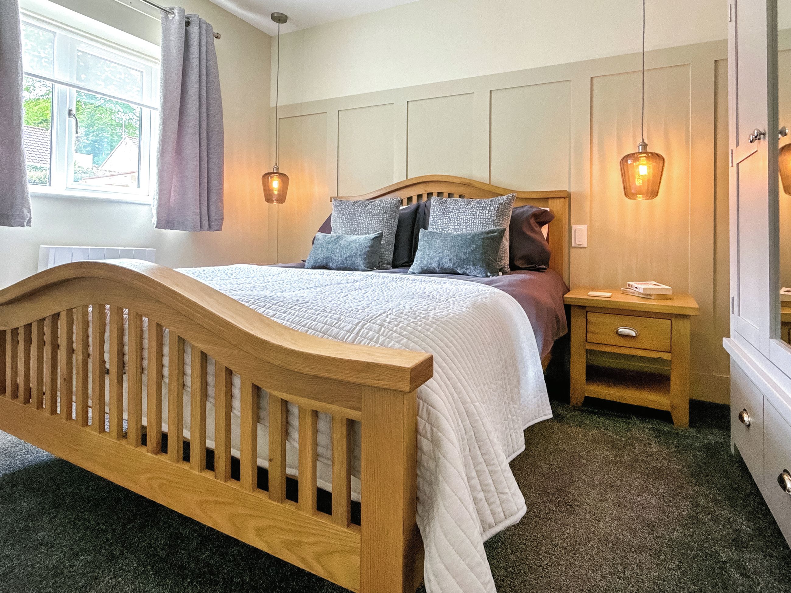 Quarto com cama de madeira, mesa de cabeceira e espelho.