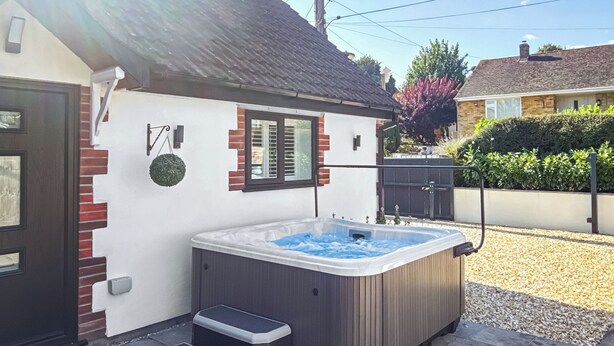 Een bubbelbad met treden, een bakstenen muur en een raam met luiken.