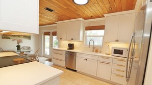 A modern kitchen with white cabinetry, stainless steel appliances, and a wooden ceiling.