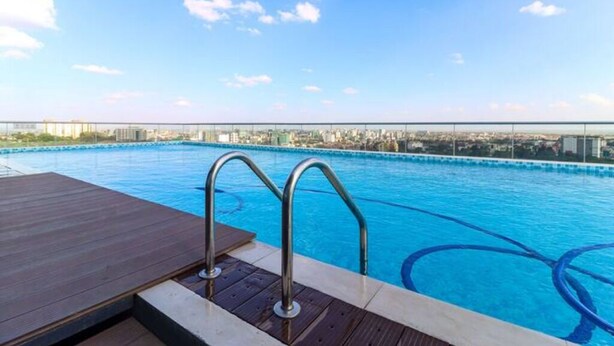 Une piscine sur le toit, entourée de rampes en métal et dotée d’une terrasse en bois.