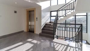 Un intérieur spacieux agrémenté d’un escalier moderne et de grandes fenêtres.