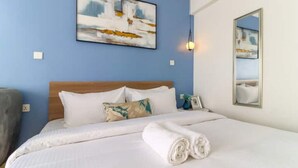 Une chambre d’hôtel avec un lit soigneusement fait, un tableau accroché au mur et un miroir qui reflète la pièce.