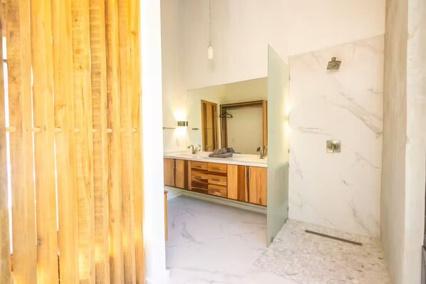A modern bathroom with a wooden vanity, a large mirror, and marble flooring.