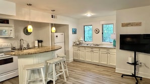 Una cocina moderna con armarios blancos, encimera de granito y una isla integrada con taburetes.