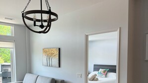 A modern living room with a grey sofa, a wooden dining table, and a hanging light fixture.